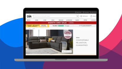 The image is a laptop screen with the Oak Furnitureland website featured